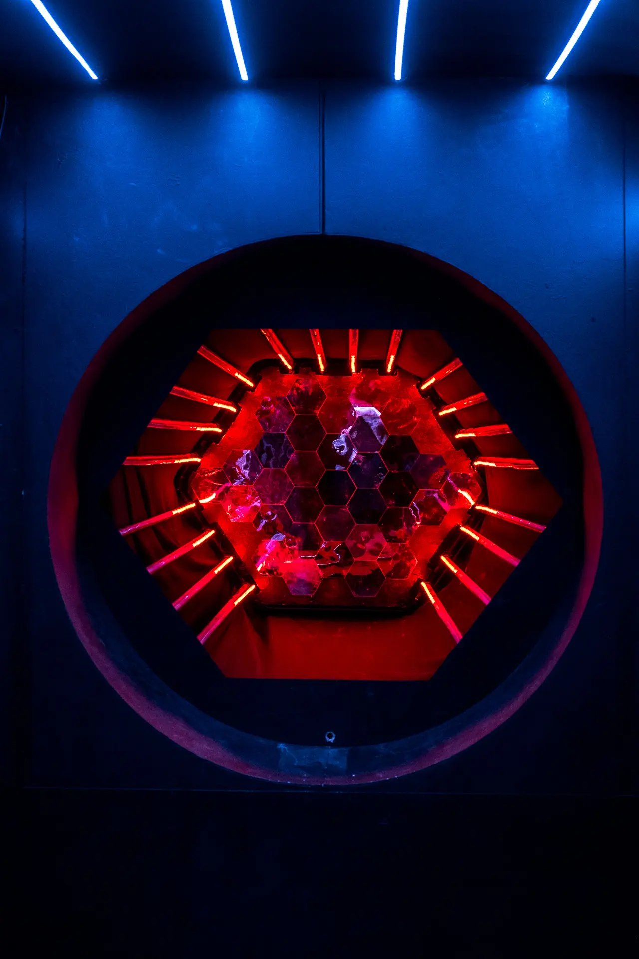 Full view of the portal-style light sculpture with surrounding speakers and dark exhibition backdrop