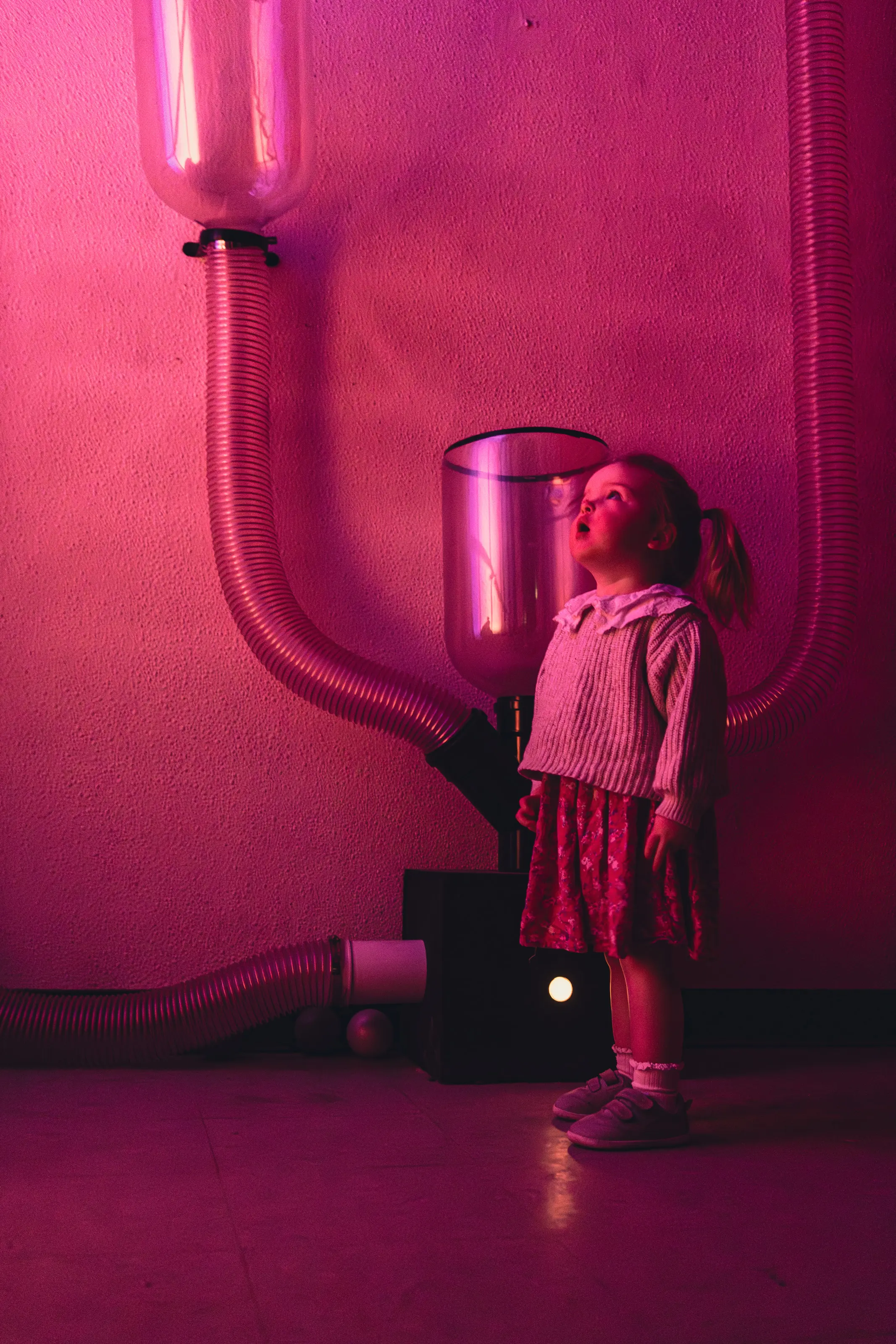 Portrait view of a participant standing beneath suspended tubes and glowing red lighting effects